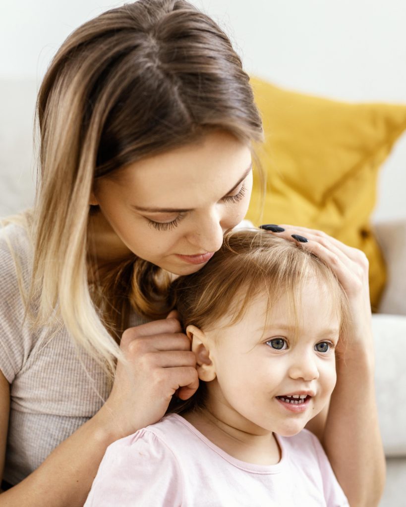 jolie maman regardant l'oreille de sa petite fille